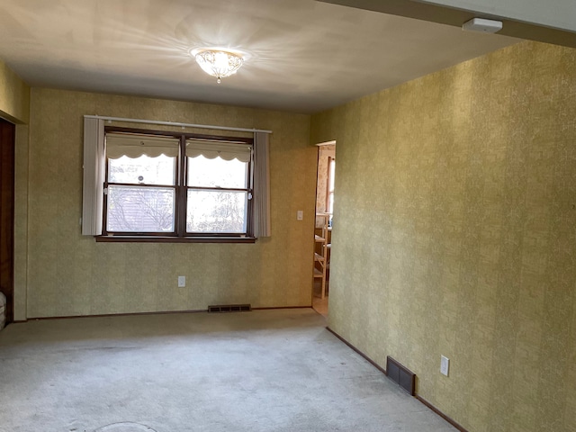 spare room with visible vents, carpet, and wallpapered walls