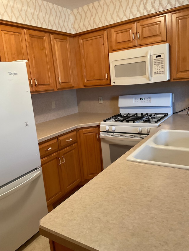 kitchen with brown cabinetry, white appliances, and light countertops