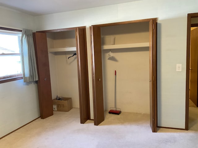 unfurnished bedroom featuring two closets and carpet flooring