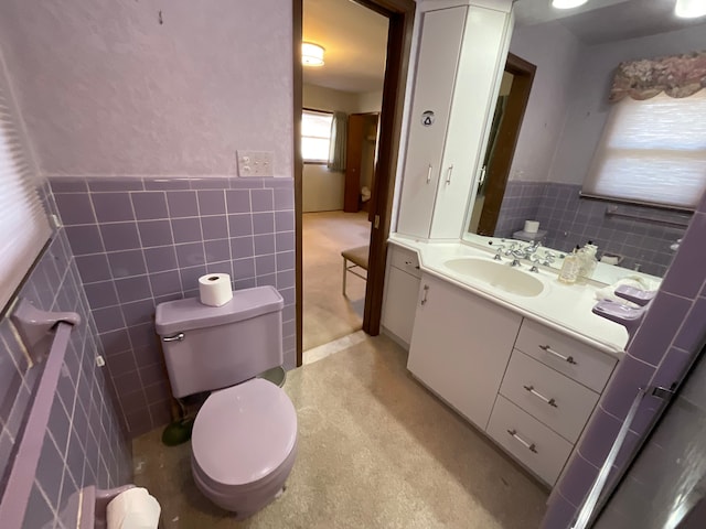 bathroom featuring vanity, tile walls, toilet, and a wainscoted wall