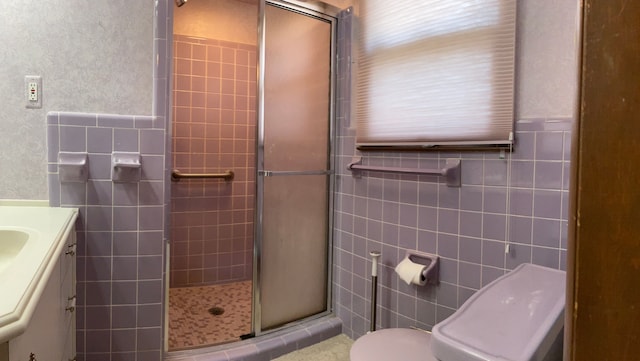 full bath featuring vanity, tile walls, toilet, and a stall shower