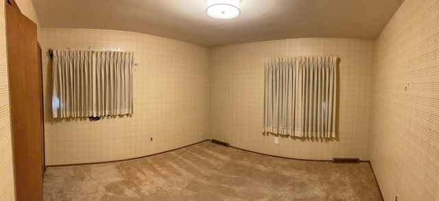 carpeted spare room with lofted ceiling and visible vents