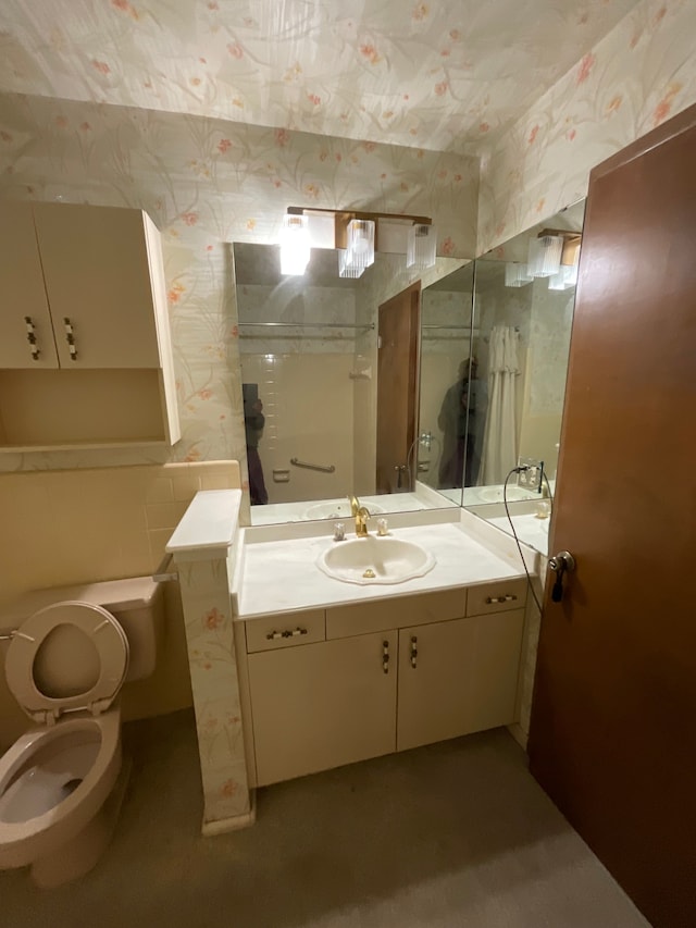 bathroom featuring toilet, wallpapered walls, and vanity