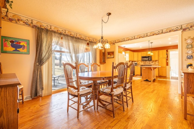 dining area featuring baseboards, light wood-style floors, an inviting chandelier, and a textured ceiling