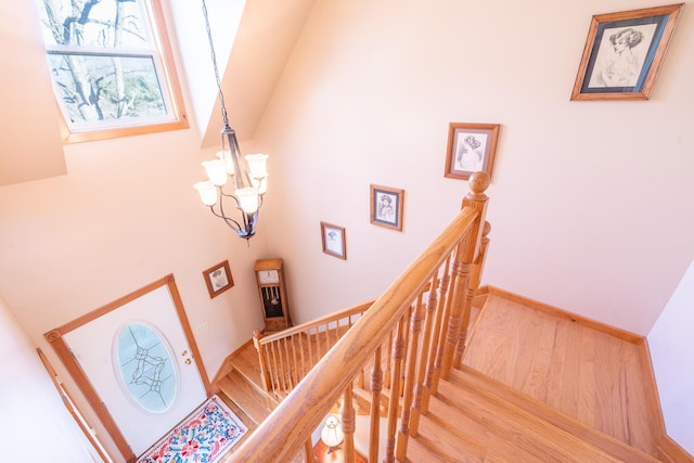 stairway with a chandelier, baseboards, and wood finished floors