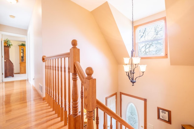 stairway featuring visible vents, wood finished floors, and a chandelier