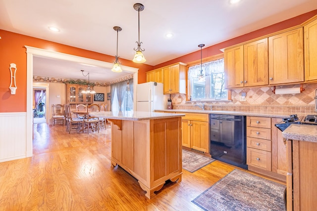 kitchen with a wainscoted wall, light wood finished floors, a kitchen island, freestanding refrigerator, and dishwasher