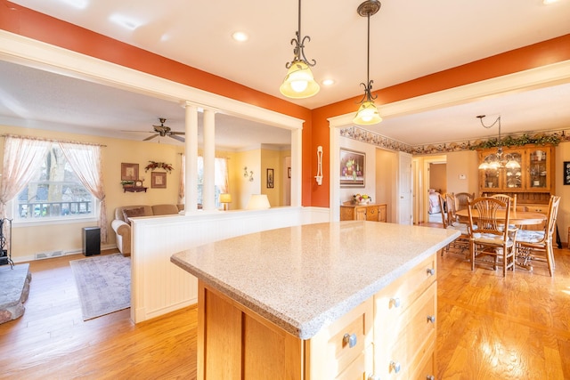 kitchen with visible vents, a ceiling fan, decorative light fixtures, a center island, and light wood-style floors