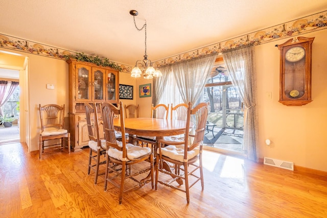 dining room with an inviting chandelier, baseboards, visible vents, and light wood-type flooring