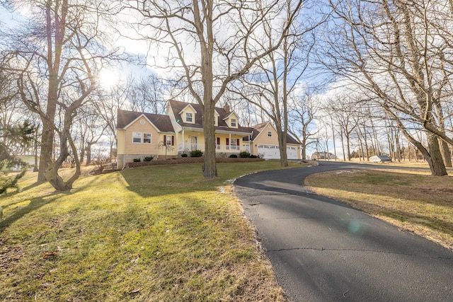 new england style home featuring a porch, driveway, and a front lawn