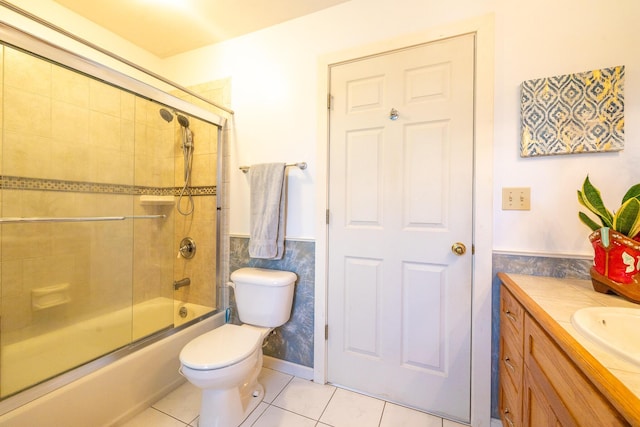 full bathroom featuring tile patterned floors, a wainscoted wall, toilet, combined bath / shower with glass door, and vanity