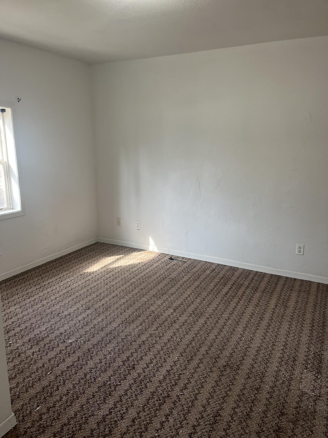 unfurnished room with dark carpet and baseboards