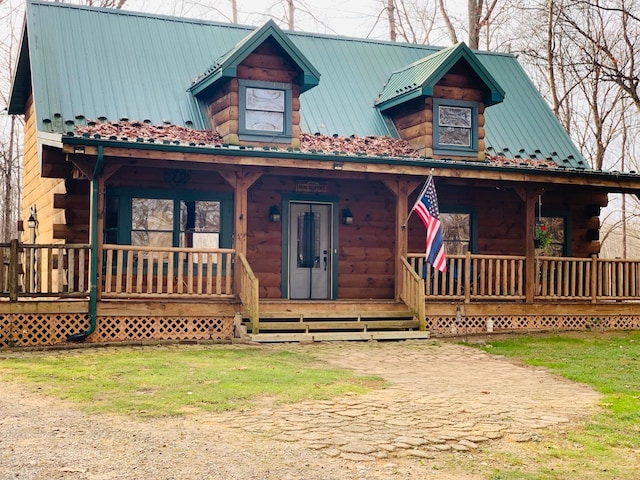 view of front facade with log exterior, a porch, and metal roof