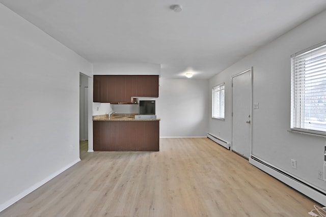 kitchen with light wood-style flooring, light countertops, a baseboard heating unit, and baseboards