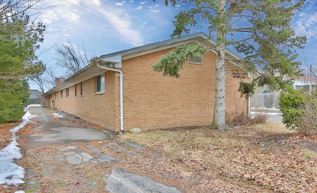 view of side of home featuring fence and brick siding