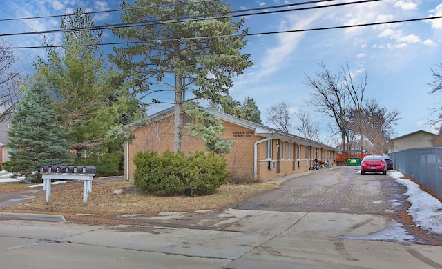 view of side of home featuring brick siding, driveway, and fence