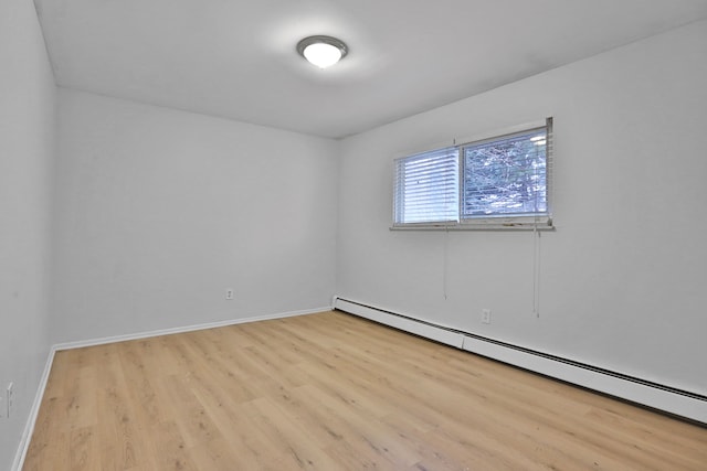 spare room featuring wood finished floors, baseboards, and baseboard heating