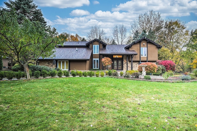 view of front facade with french doors, stone siding, roof with shingles, and a front yard