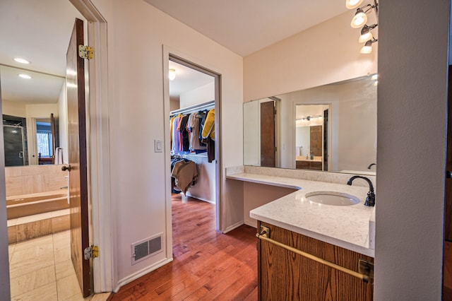 full bathroom featuring a spacious closet, visible vents, recessed lighting, wood finished floors, and vanity