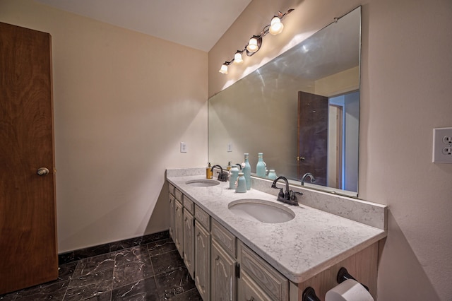 full bath with double vanity, baseboards, marble finish floor, and a sink