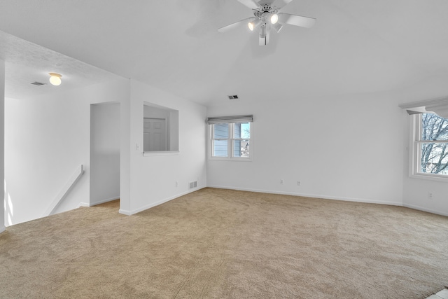 empty room featuring vaulted ceiling, carpet flooring, visible vents, and ceiling fan