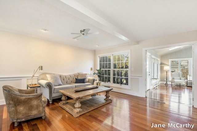 living area featuring plenty of natural light, a decorative wall, lofted ceiling, and wood finished floors