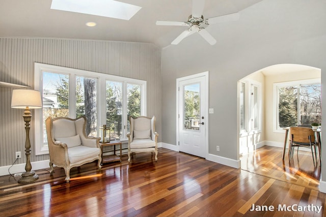 living area featuring hardwood / wood-style flooring, a skylight, a healthy amount of sunlight, and baseboards