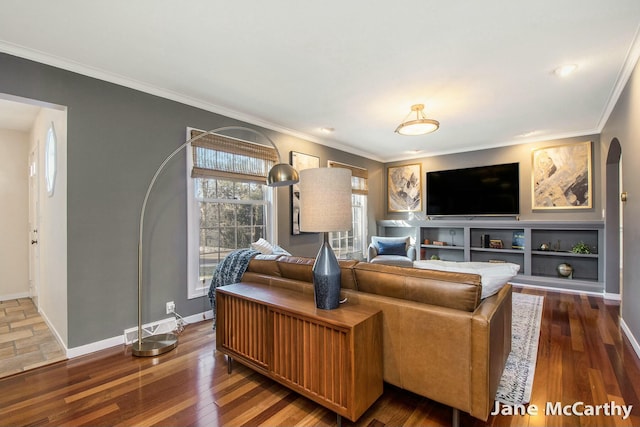 living area with arched walkways, crown molding, baseboards, and wood finished floors