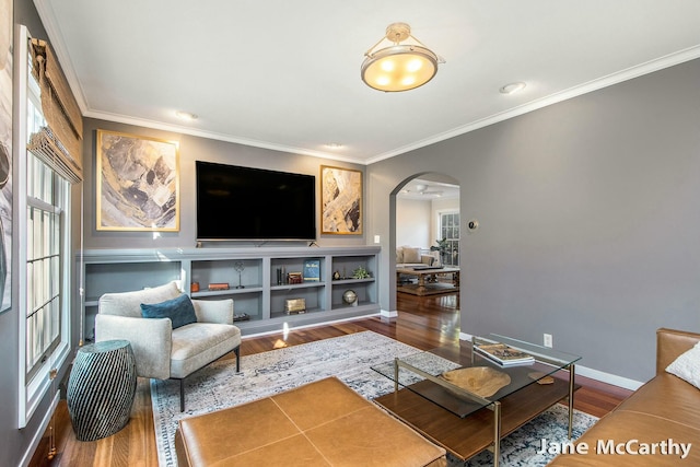 living area featuring arched walkways, a wealth of natural light, and wood finished floors