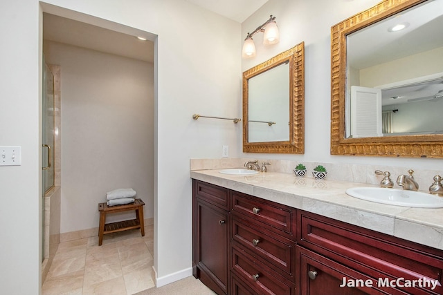 bathroom with double vanity, an enclosed shower, baseboards, and a sink