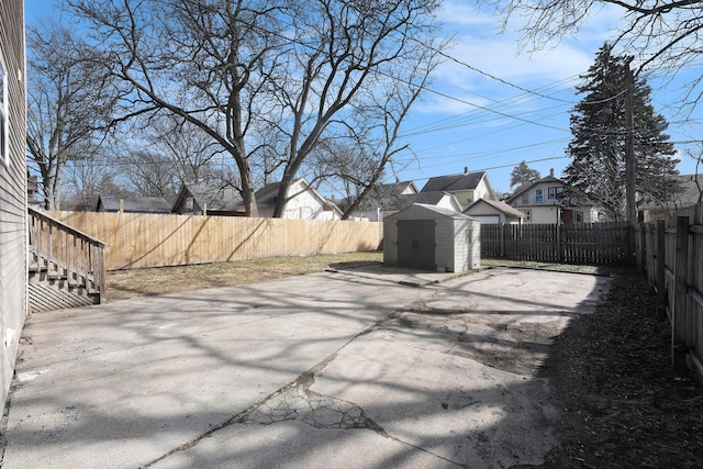 view of patio / terrace with a storage shed, an outbuilding, a fenced backyard, and a residential view