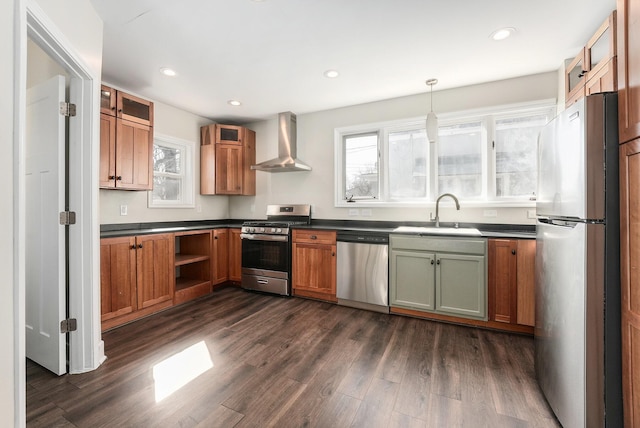 kitchen with dark wood-style flooring, a sink, appliances with stainless steel finishes, dark countertops, and wall chimney range hood