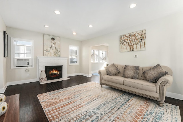 living area with cooling unit, plenty of natural light, baseboards, and dark wood-style floors