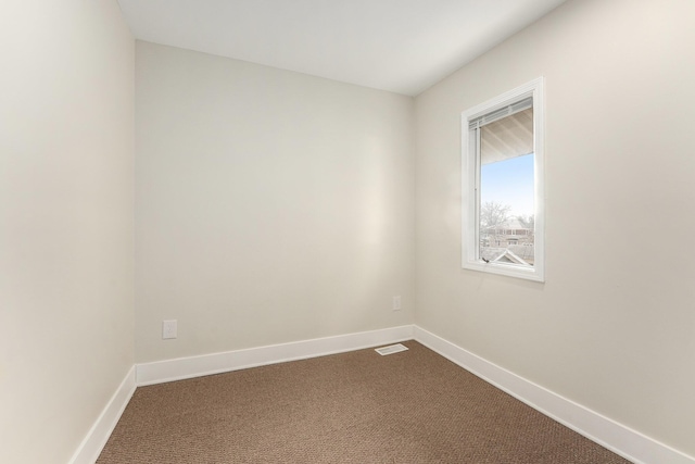 spare room featuring visible vents, baseboards, and dark carpet