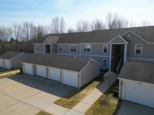 view of front of house with a garage, driveway, and a shingled roof