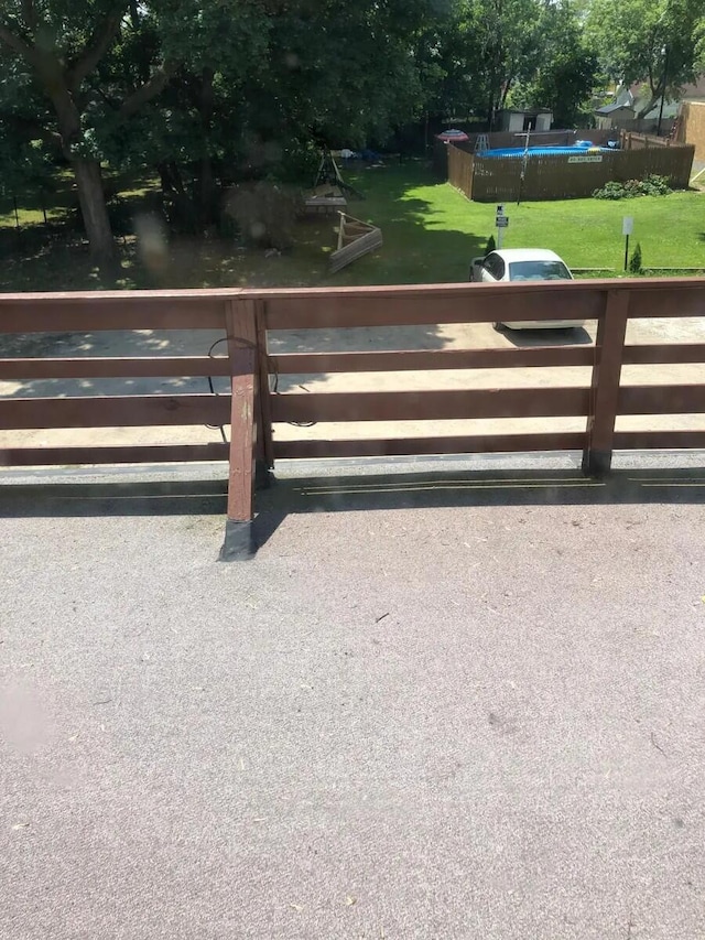 view of gate featuring a swimming pool, a lawn, and fence