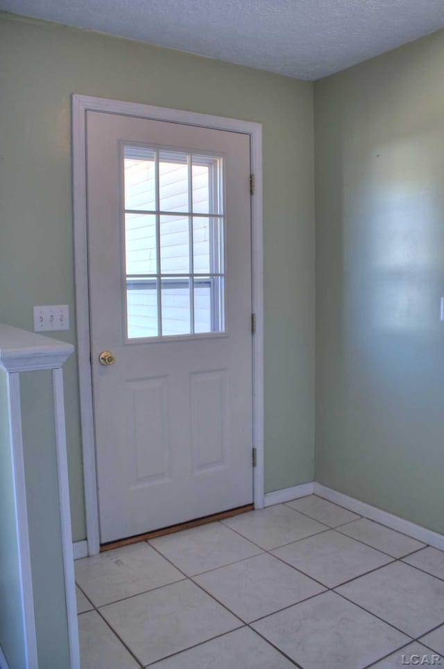 entryway with light tile patterned floors, baseboards, and a textured ceiling