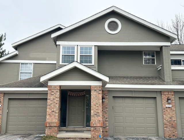 townhome / multi-family property featuring a garage, brick siding, and roof with shingles