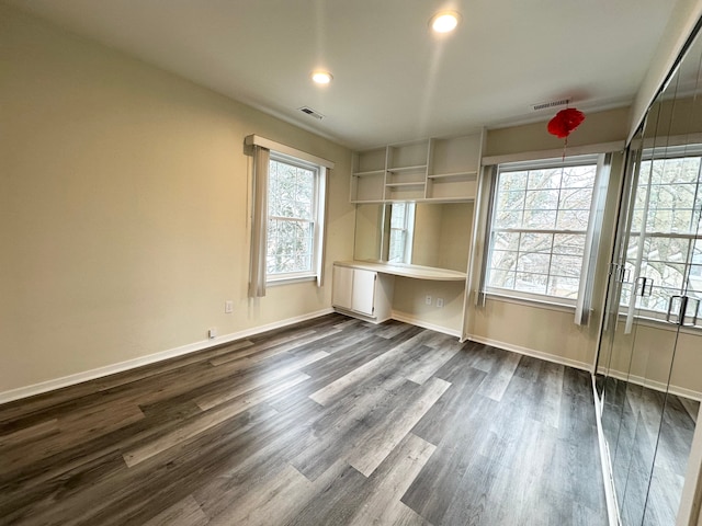 interior space featuring built in desk, baseboards, visible vents, and dark wood-style flooring