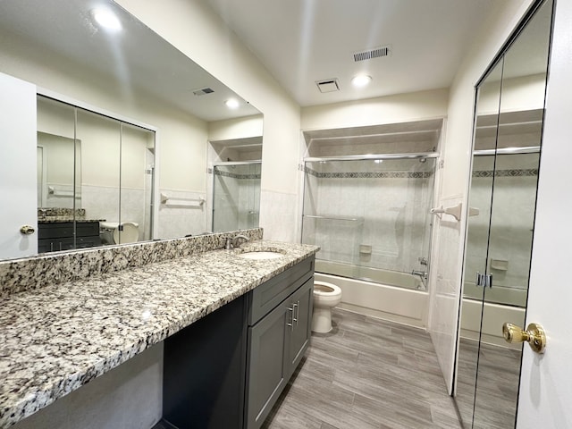 full bath with vanity, toilet, visible vents, and bath / shower combo with glass door