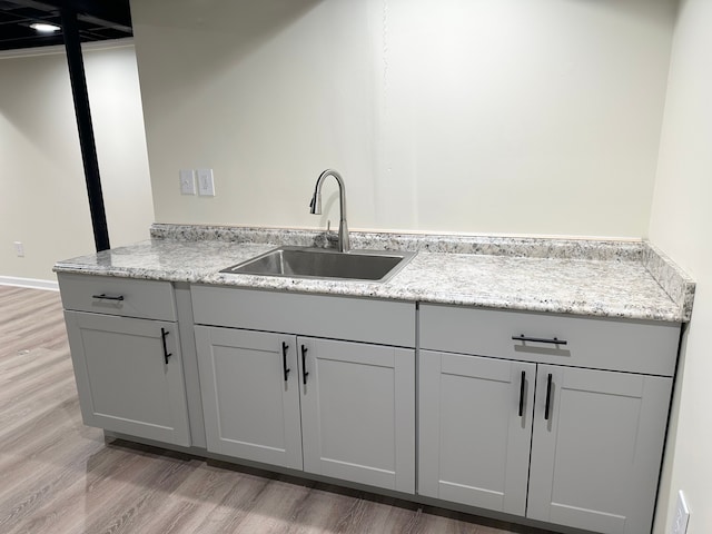 kitchen with gray cabinetry, light wood finished floors, and a sink