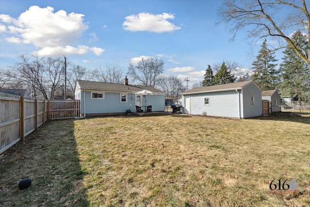 back of house featuring a yard, an outbuilding, and a fenced backyard