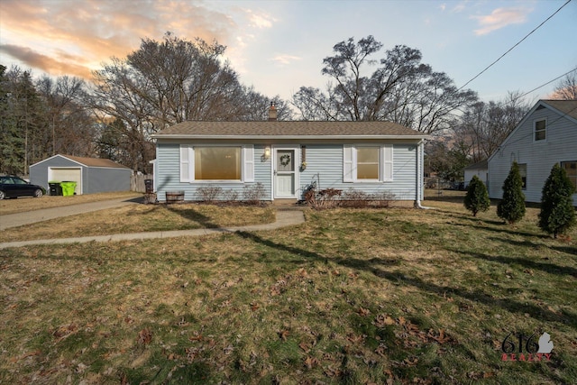 view of front of home featuring a yard, a detached garage, and a chimney