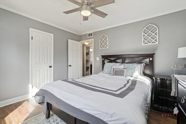 bedroom with visible vents, crown molding, baseboards, wood finished floors, and a ceiling fan