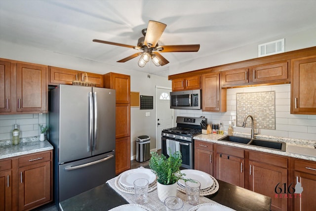 kitchen with brown cabinetry, visible vents, appliances with stainless steel finishes, and a sink