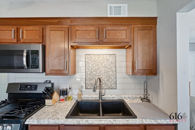 kitchen featuring a sink, brown cabinets, visible vents, and stainless steel appliances