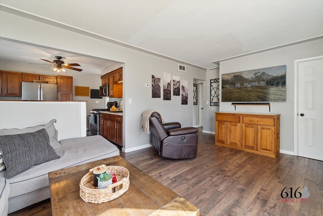 living room with visible vents, baseboards, dark wood-type flooring, and ceiling fan