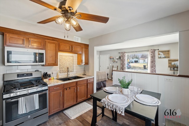 kitchen with dark wood-style floors, visible vents, a sink, appliances with stainless steel finishes, and brown cabinets