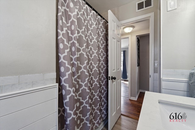 bathroom featuring visible vents, curtained shower, wood finished floors, and wainscoting