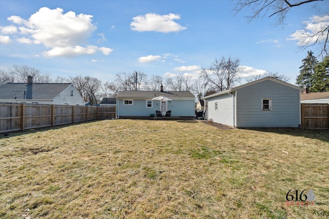 rear view of house with an outbuilding, a lawn, and a fenced backyard